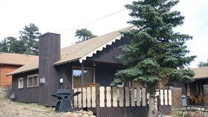 A rustic cabin with a wooden exterior, a chimney, and a fenced yard. - Lazy R Cottages: 8 (Estes Park)