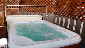 Un bain à remous avec une terrasse en bois et une clôture en treillis en arrière-plan.