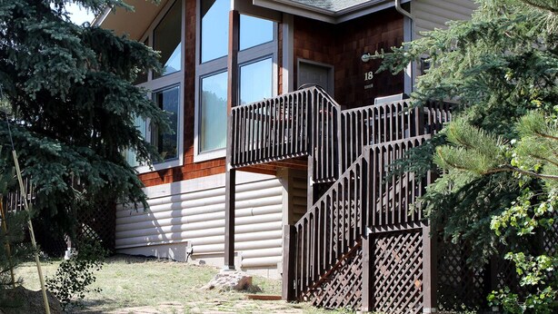 Una casa de dos pisos con un balcón de madera y una escalera que sube al piso superior.