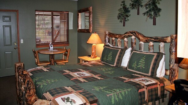 Een slaapkamer met een groot bed, een houten hoofdeinde, een tafeltje, een stoel en een lamp.