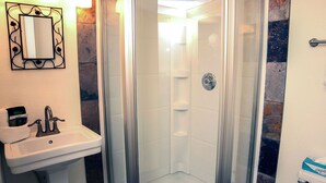 A bathroom with a glass-enclosed shower, a sink with a mirror, and a towel rack.