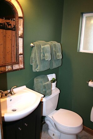 A bathroom with a white sink, a toilet, and two towels hanging on a rack. - Triple R Cottages: 6 (Estes Park)