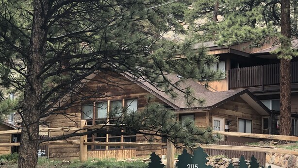 Une pancarte indiquant que les chalets de Timber Creek ont des chambres disponibles, avec une vue sur les montagnes en arrière-plan et une structure en bois.