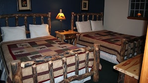 A room with two wooden beds, each with a quilt featuring animal prints. There is a nightstand with a lamp between the beds.