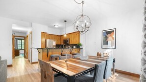 Una cocina moderna con armarios de madera, un refrigerador de acero inoxidable y una lámpara colgante.