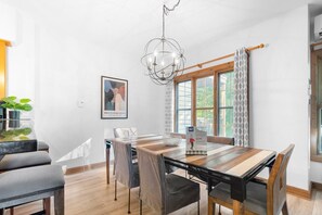 Een moderne eetruimte met een houten tafel, stoelen en een kroonluchter.