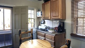 A compact kitchen with wooden cabinets, a microwave, a stove, and a sink. - Triple R Cottages: 7 (Estes Park)