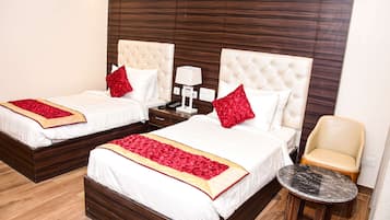 A hotel room with two beds, a small table, and a chair.