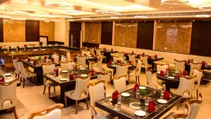 A spacious dining area with multiple tables and chairs, a central bar, and a modern ceiling design.