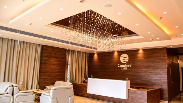 A hotel reception area with a modern design, featuring a reception desk, seating area, and a chandelier.