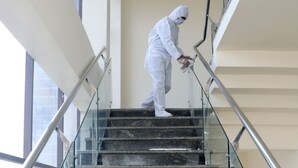 A person in white protective clothing painting a staircase.