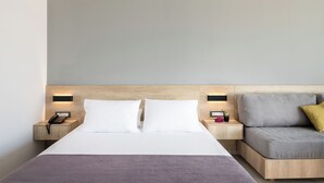 A modern hotel room with a bed, bedside tables, a sofa, and a wooden headboard. - Chq Galini Palace (Platanias)