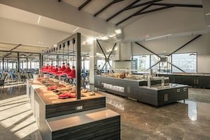 A modern buffet setup with multiple food stations and seating areas. - Chq Galini Palace (Platanias)
