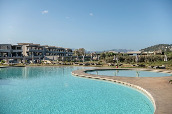 Un resort con una piscina grande, tumbonas y vistas del paisaje circundante.