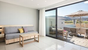 A modern living room with a sofa, a wooden coffee table, and a glass door leading to an outdoor patio with a pool and umbrellas. - Chq Galini Palace (Platanias)