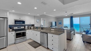 Eine moderne Küche mit weißen Schränken, Edelstahlgeräten und einer großen Kochinsel.