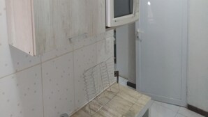 Una cocina con armarios de madera, un microondas y una puerta con un pequeño letrero.