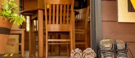 A wooden door with a pair of hiking boots and a potted plant on the threshold.