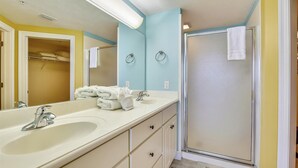 Une salle de bain avec deux lavabos, un miroir, un porte-serviettes et une douche.