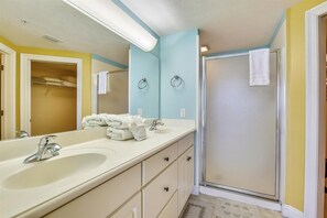 Une salle de bain avec deux lavabos, un miroir, un porte-serviettes et une douche.