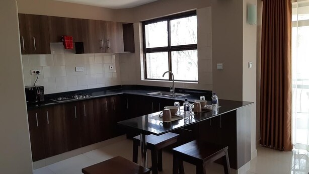 Een moderne keuken met donkerhouten kasten, een centraal eiland met krukken, een raam met jaloezieën en uitzicht op de omgeving.