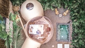 Una estructura circular amb una cúpula transparent, una petita piscina i una zona de seients amb taula i cadires.