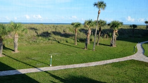 A grassy area with a paved path and palm trees. - CP 421 2 Bedroom Ocean View Condo - Paradise Vacation Rental in Ocean Village (Fort Pierce)