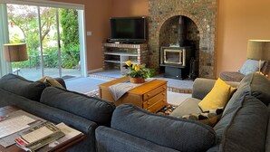 Una sala de estar con chimenea de piedra, televisor de pantalla plana y sofá.