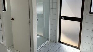 Ett badrum med en duschkabin med glasväggar, vita kakelväggar och en dörr av frostat glas.