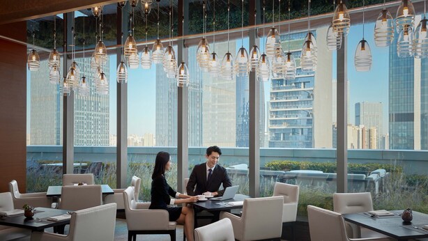 A modern conference room with large windows, multiple tables, and chairs. - Sheraton Beijing Lize Hotel (Beijing)