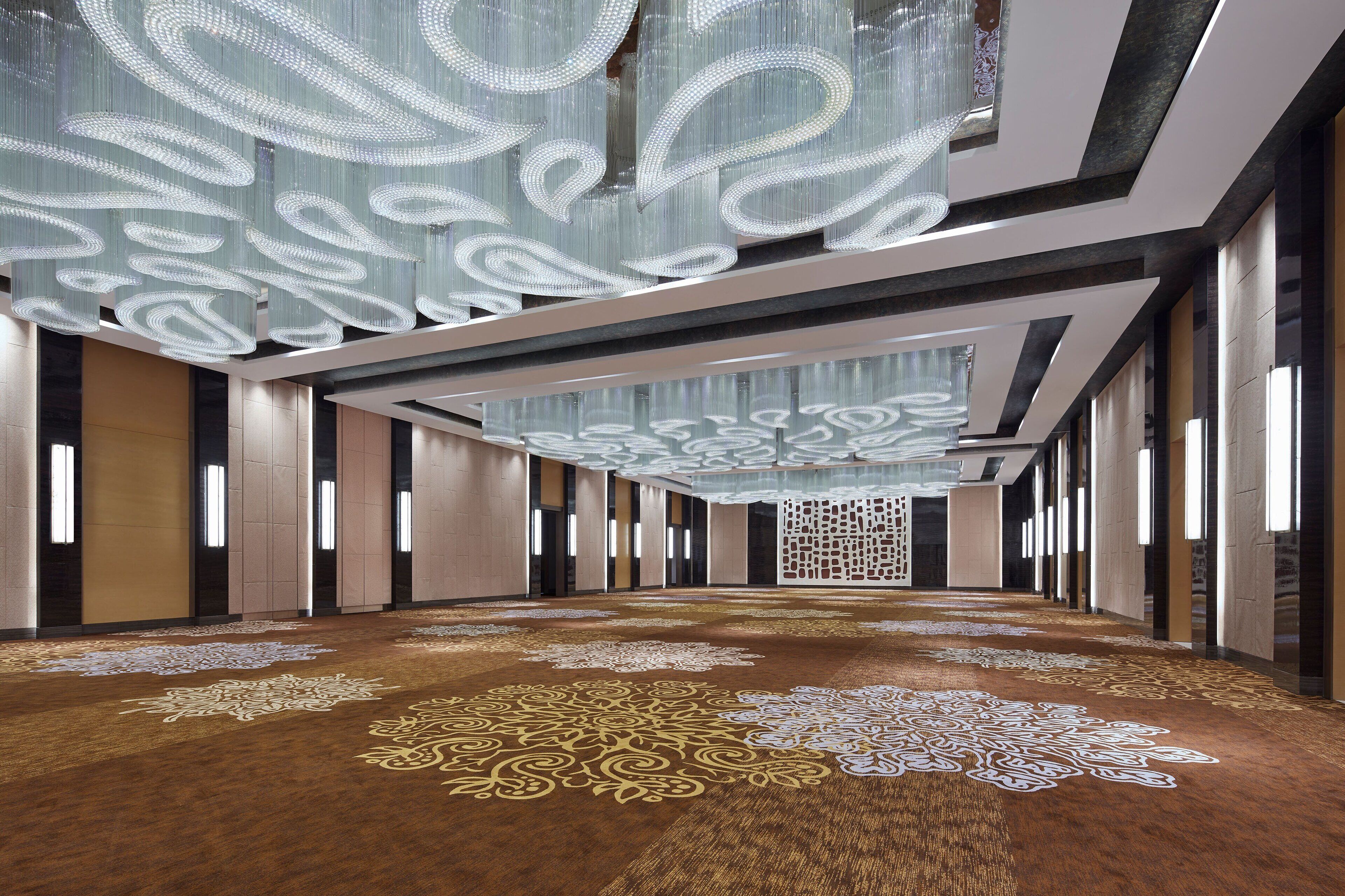 A spacious hallway with patterned carpet, modern lighting, and a decorative ceiling.