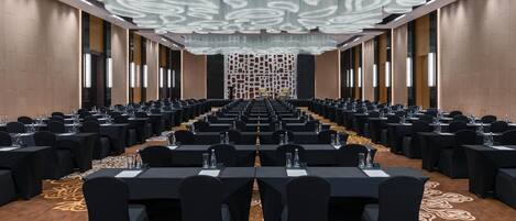 A conference room with rows of tables and chairs, a patterned carpet, and a decorative ceiling.
