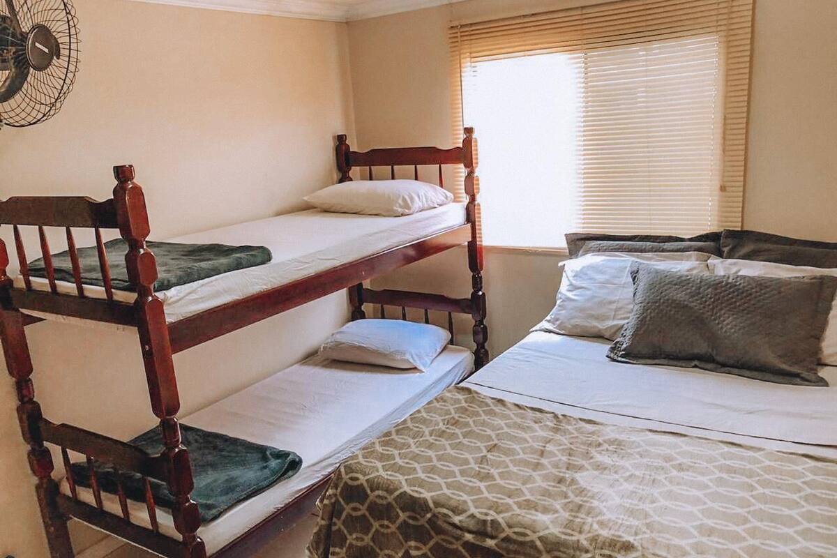 Una habitación con literas, un ventilador y una ventana con persianas.
