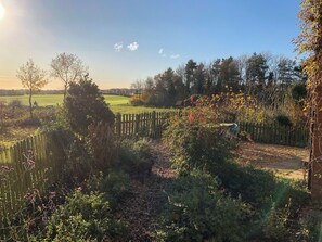 A garden with a wooden fence, various plants, and a path leading to a field. - 4 bedroom accommodation in Hempstead, near Holt (Hempstead, near Holt)
