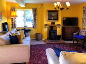 A living room with a sofa, armchair, and a fireplace. - 4 bedroom accommodation in Hempstead, near Holt (Hempstead, near Holt)