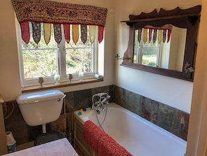 A bathroom with a toilet, sink, and bathtub. There are decorative curtains over the windows and a mirror above the bathtub. - 4 bedroom accommodation in Hempstead, near Holt (Hempstead, near Holt)