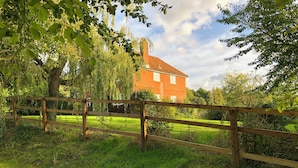 A wooden fence in a grassy area with a brick house in the background. - 4 bedroom accommodation in Hempstead, near Holt (Hempstead, near Holt)