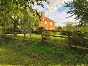 A wooden fence in a grassy area with a brick house in the background. - 4 bedroom accommodation in Hempstead, near Holt (Hempstead, near Holt)