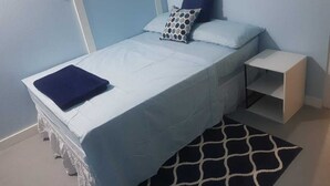 A bedroom with a bed, pillows, a bedside table, and a rug. - Careffe Suites Studio 4 - 5 mins to from Rodney Bay Village (Monchy)