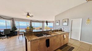 A spacious kitchen with a large island, a ceiling fan, and a view of the sea. - Breathtaking Panoramic Views Of The Caribbean Sea From This Luxury Villa (St. Thomas)