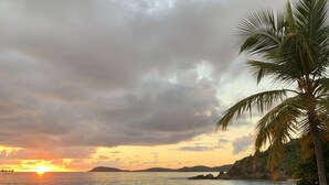 A beach with a sunset, palm trees, and a view of the water. - Breathtaking Panoramic Views Of The Caribbean Sea From This Luxury Villa (St. Thomas)
