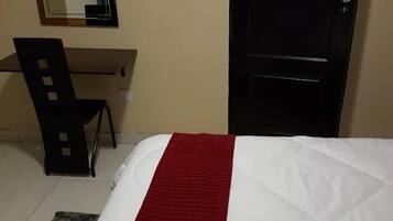 A hotel room with a bed, a desk, and a chair.