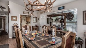Comedor rústico con una mesa de madera dispuesta para el desayuno, rodeada de sillas tapizadas en cuero animal.