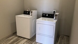 A laundry room with two stacked front-loading washing machines and a dryer. - Crystal Inn Downtown (Houston)