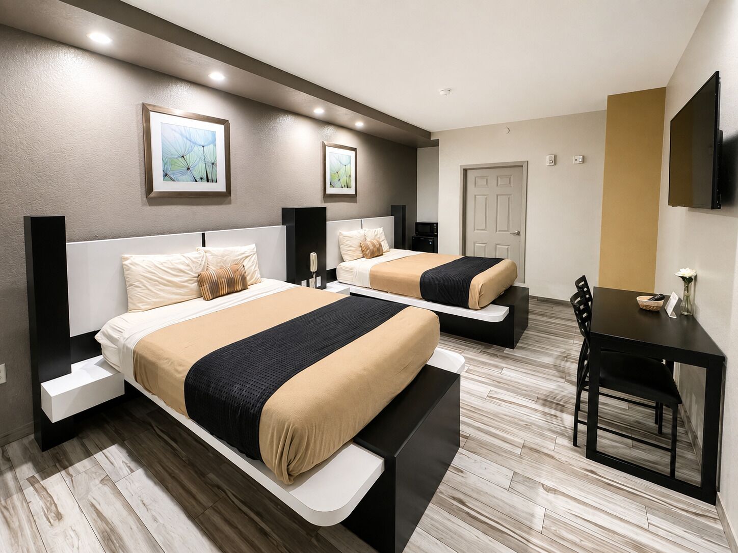 Habitació d'hotel amb dos llits, un escriptori i una cadira.