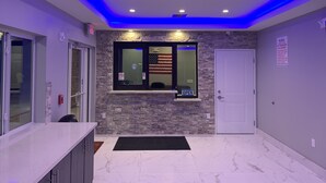 A reception area with a marble floor, a reception desk, a window with an American flag, and a door. - Crystal Inn Downtown (Houston)