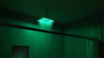 A room with a green-lit chandelier, a visible window, and a curtain rod.