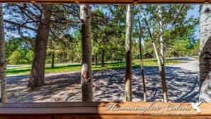 A wooden pergola with a view of a park area, including trees and a building in the background. - Timbers Lodge | Your Ruidoso Retreat w/ Hot Tub Bliss, Wildlife Views & Cozy Comforts (Ruidoso)