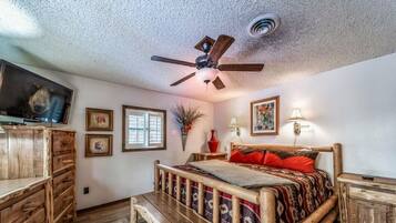 A bedroom with a wooden bed, a ceiling fan, a TV, and a window.