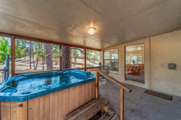 Een hottub met een houten terras, een overdekt buitengebied en uitzicht op de natuur.